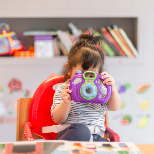 Bambina che gioca a un tavolo davanti a una libreria