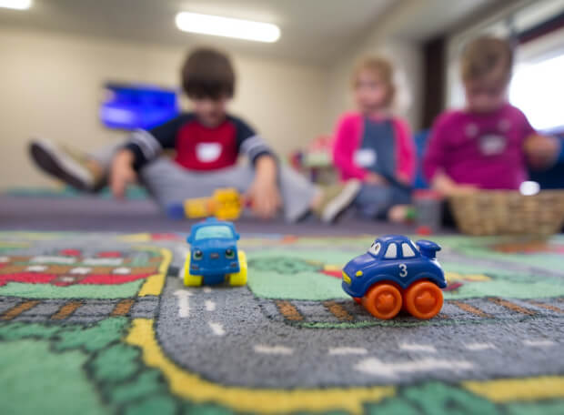 Bambini che giocano con le macchinine su un tappeto in sezione