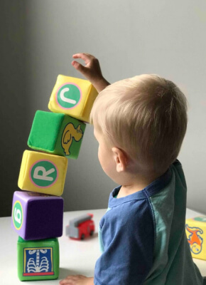 Bambino che impila cubi colorati con le lettere