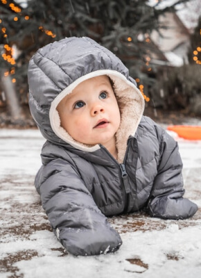Bambino piccolo con la tuta imbottita che gioca all'aperto