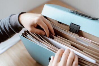 Mani che consultano un raccoglitore di documenti societari